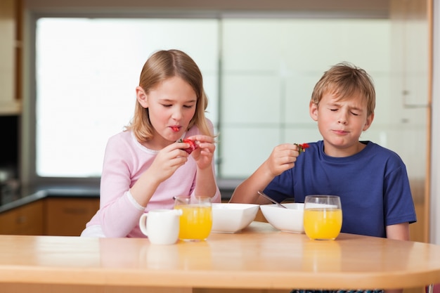 Siblings eating strawberries for breakfast