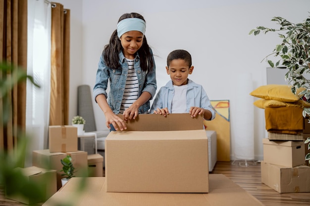 Siblings girl and boy cooperate help parents with packing things for moving unpacking cardboard