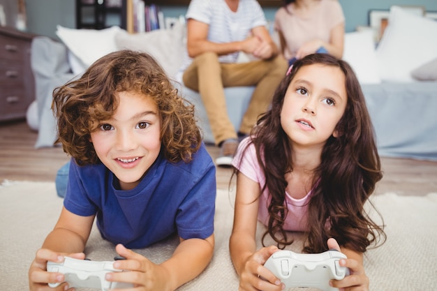 Siblings with playing video game on carpet