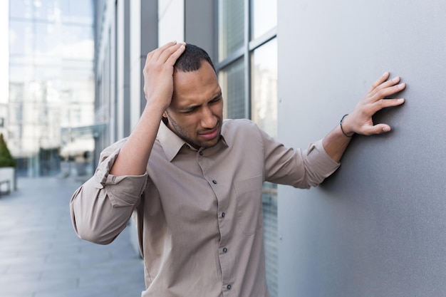 Sick african american man outside modern office building man has severe headache and migraine worker