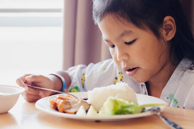 Sick asian child girl eating healthy food for lunch by herself while stay in private patient rooms in the hospital. Healthcare and lifestyle concept.