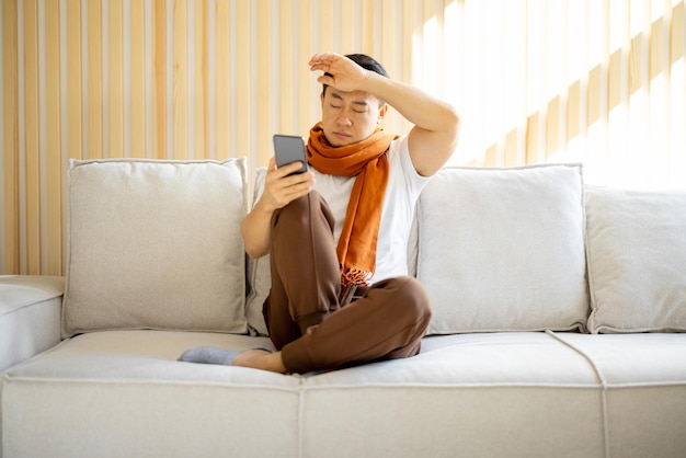 Sick asian man coughing and using smartphone