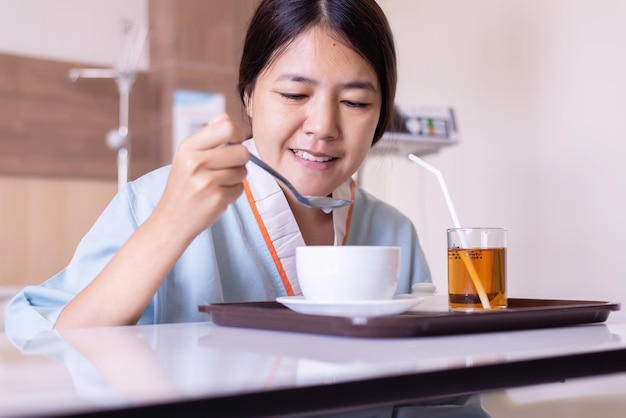 Sick asian woman patient eating meal on sickbed in the hospital