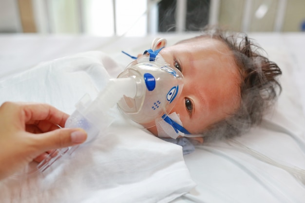 Sick baby boy applying inhale medication by inhalation mask to cure Respiratory Syncytial Virus (RSV)