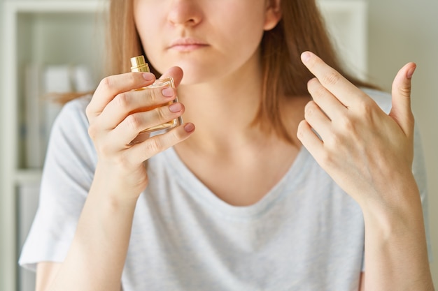 Sick female sniffing perfume bottle has one of possible symptoms of corona virus infection