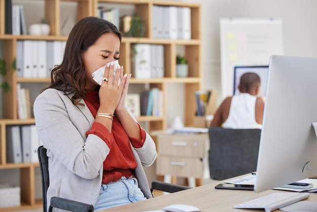 Sick ill and sneezing business woman with cold flu or allergy while working at office Workaholic or manager trying to work at desk with covid disease virus or bad work life balance at workplace