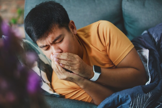 Sick man covered with a blanket coughing