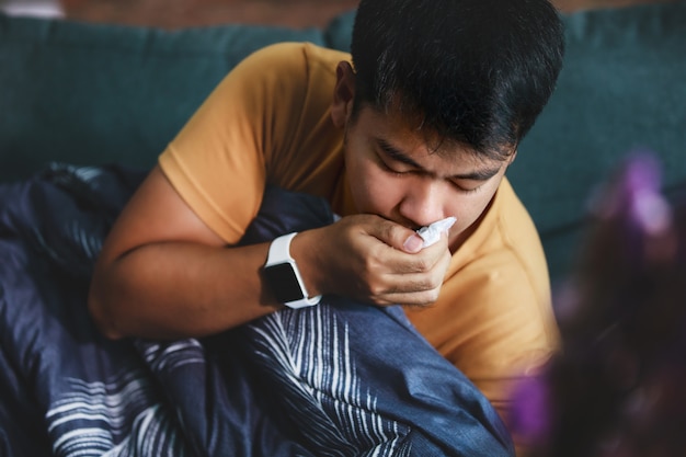 Sick man covered with a blanket lying on the sofa