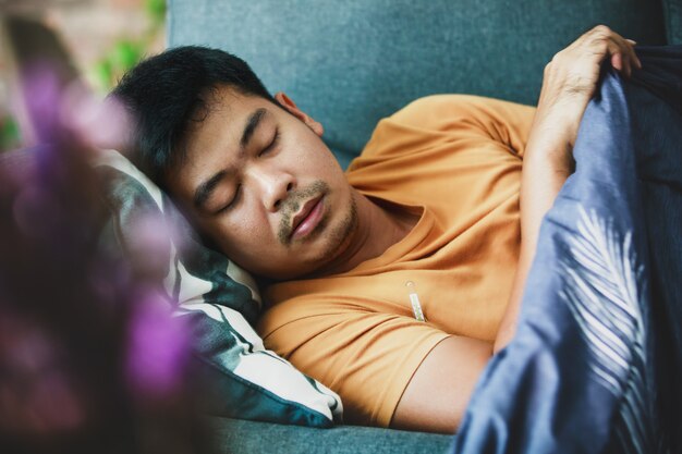 Sick man covered with a blanket lying on the sofa