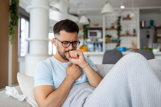 Sick man holding his chest in pain while coughing in the living room Sore throat and cough man with lung pain at home health problems concept