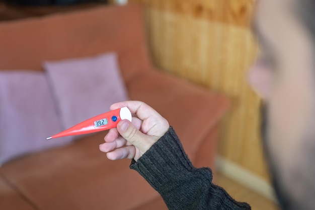 Sick man looking at the high temperature marked on the thermometer after checking himself