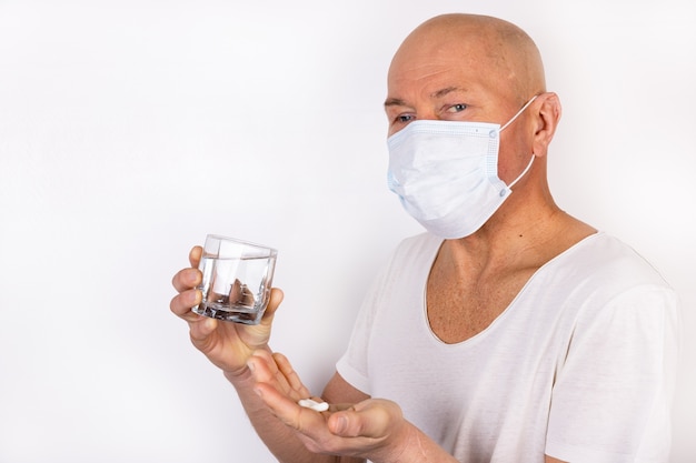 A sick man in a medical mask stands on a white