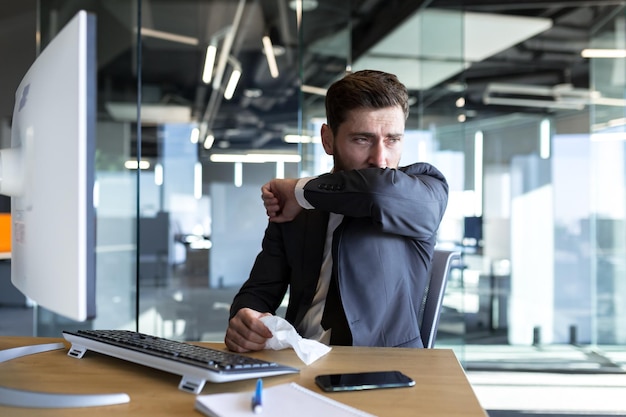 Sick man working in the office businessman has a bad cough working in a modern office at the computer