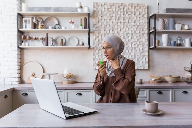 Sick muslim woman in hijab at home woman has severe sore throat sore throat uses pain relief spray