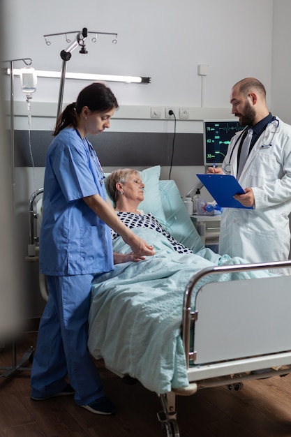 Sick senior woman getting medication through an intravenous line, laying in hospital bed