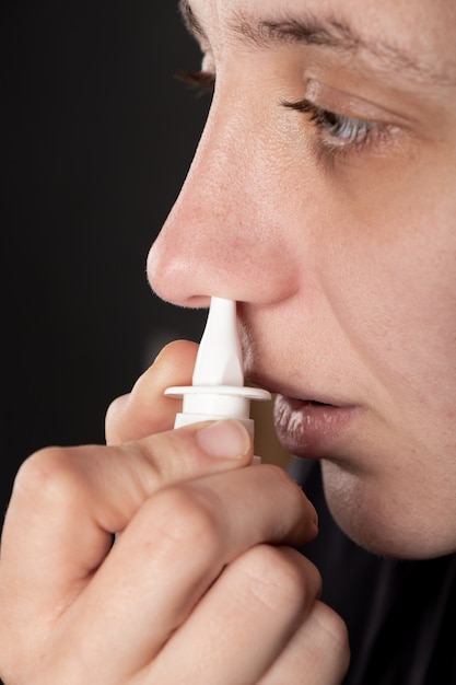 Sick woman puffs nasal spray in her nose