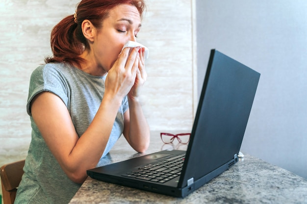 Sick woman sitting at desk with laptop from home office