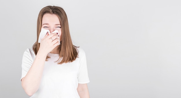 Sick woman suffers from a cold and blows her nose into a napkin. The concept of medicine and seasonal colds with copyspace.