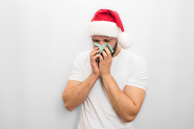 Sick young man in red hat stands and sneezes in napkin. He is ill. Guy in unhappy. 