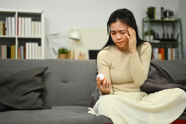 Sick young woman reading labels instruction on medicine bottle Health care and medicine concept