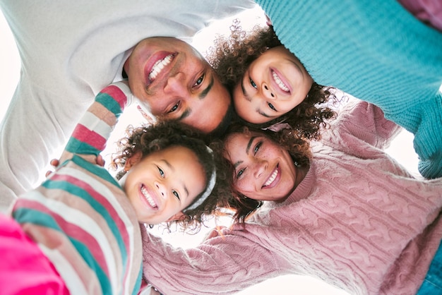 Side by side, to infinity and beyond. Low angle shot of a couple and their two daughters standing in a huddle.