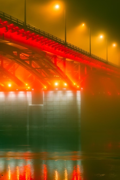 Side night view of the illuminated bridge in foggy weather Bridge in the fog