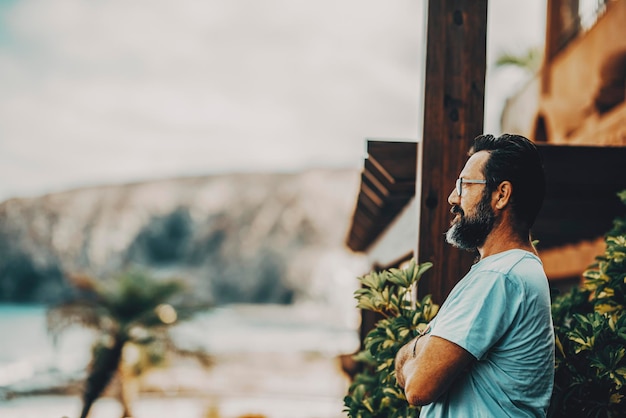 Side portrait of standing man looking in fron tof him and enjoying outdoor leisure activity alone Bearded mature people in the home garden Copy space and defocused background