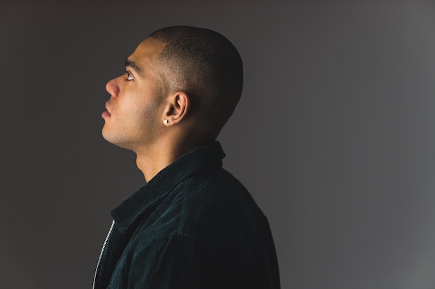 Photo side profile shot of young african american man with buzz cut on a grey dark studio background