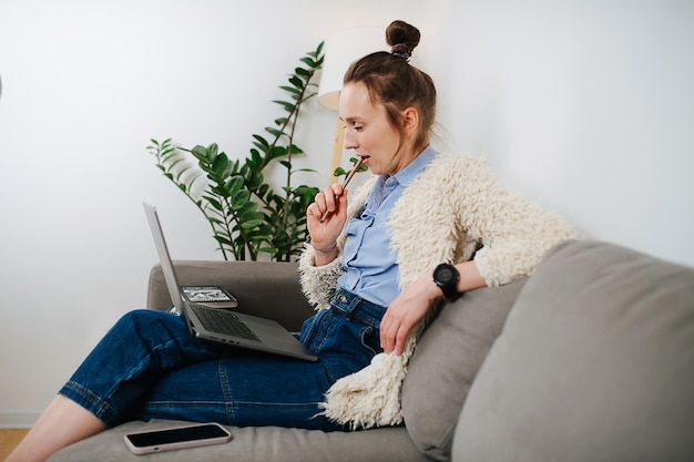 Side view of a 30 year old business woman sitting on a couch looking at camera