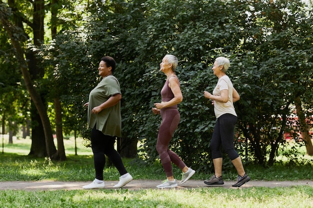 Photo side view active senior women jogging in park outdoors and enjoying sports