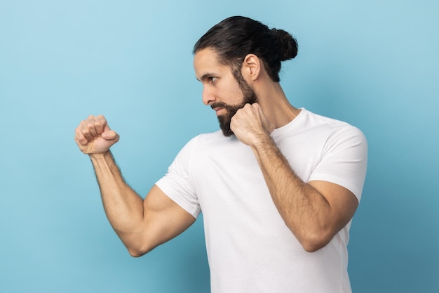 Side view of aggressive man with beard wearing Tshirt holding clenched fists up ready to boxing