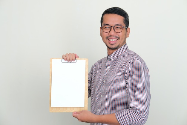 Side view of Asian man smiling to camera while holding blank white paper