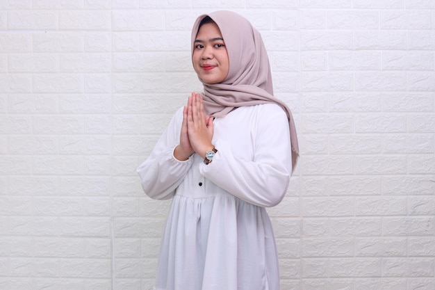 Side view of Asian muslim teenager wearing hijab gives greeting hands for eid mubarak