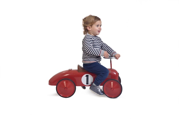 Side view of a baby boy playing with toy car on white background