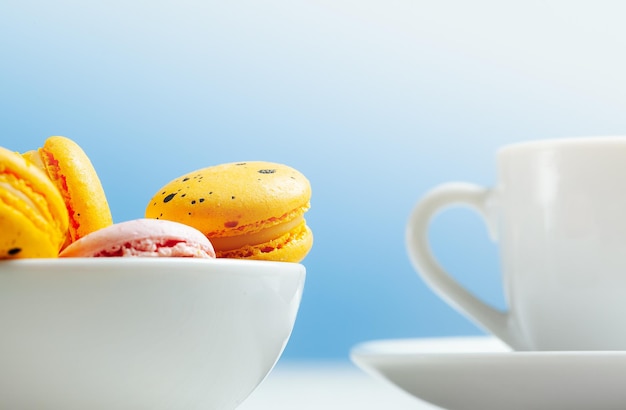 Side view of a bowl with many colorful speckled pasta and a white cup and saucer