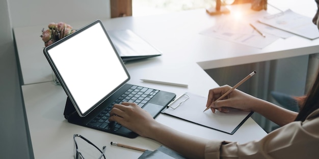 Side view of a businesswoman working on a laptop blank white screen at office Mock up