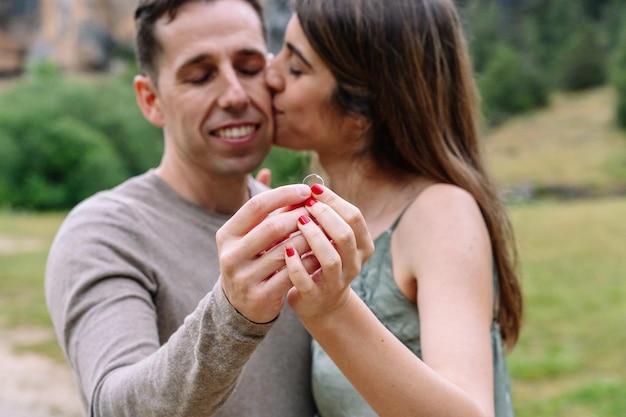 Side view of caucasian couple engaged kissing with love. Horizontal view of young couple holding an engagement ring. People and love concept.