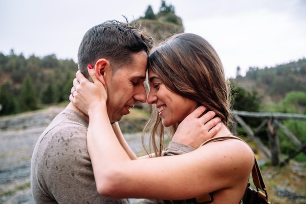 Side view of caucasian couple in love kissing and hugging. Horizontal view of couple kissing with love outdoors in nature background. People and travel concept.