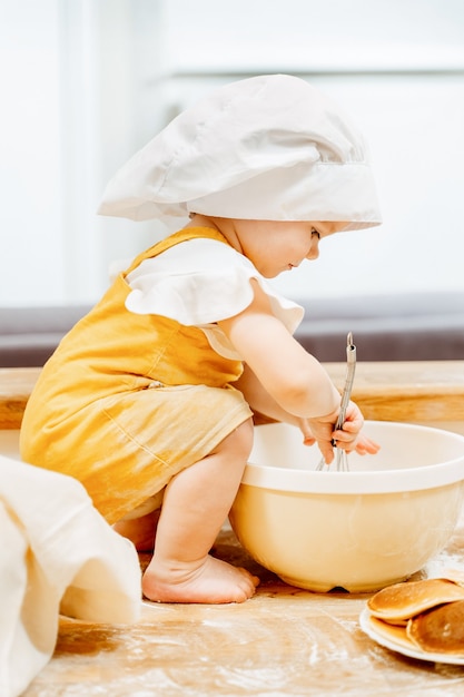 Side view of a charming one and a half year old girl in a cook suit