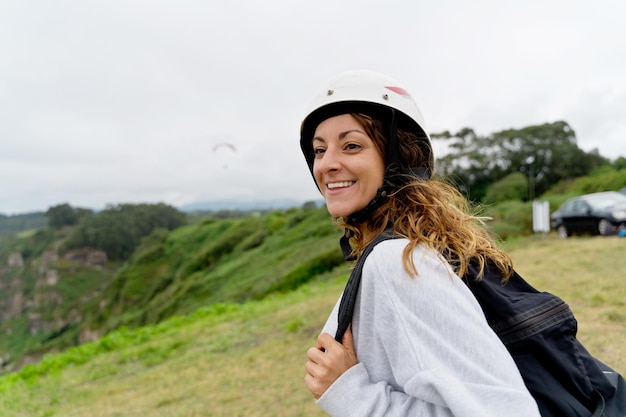 Side view of cheerful woman with paragliding equipment outdoors. Panoramic view of adventurous woman practicing risky sports. Adventure and sport lifestyle.