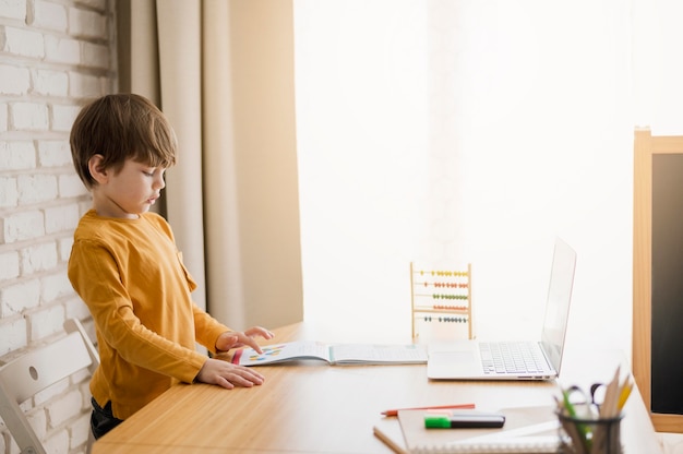 Side view of child at home studying at desk