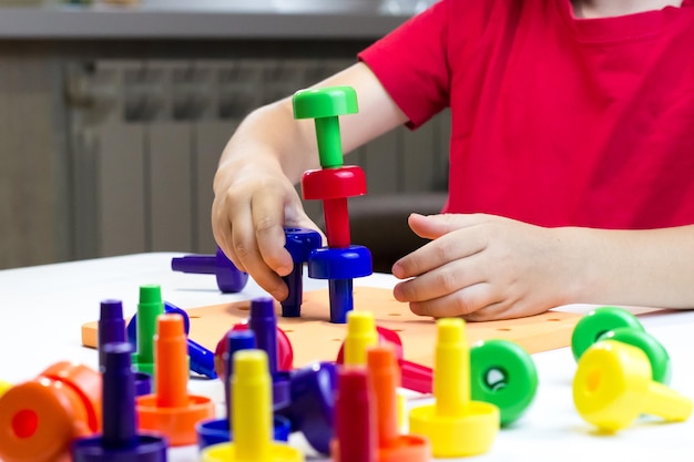 Side view of a child playing with a colored plastics constructor Building turrets