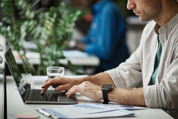 Side view close up of adult man using laptop while enjoying work in office copy space