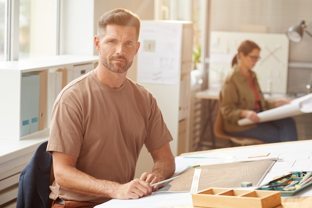 Side view close up of unrecognizable male architect drawing blueprints and plans at workplace, 