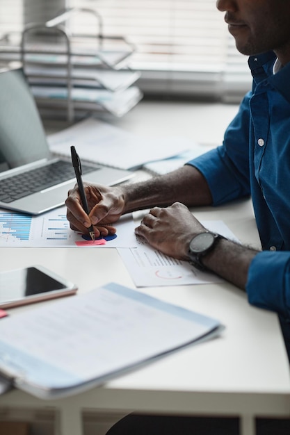 Side view close up of young africanamerican man working at desk in office and writing notes copy space