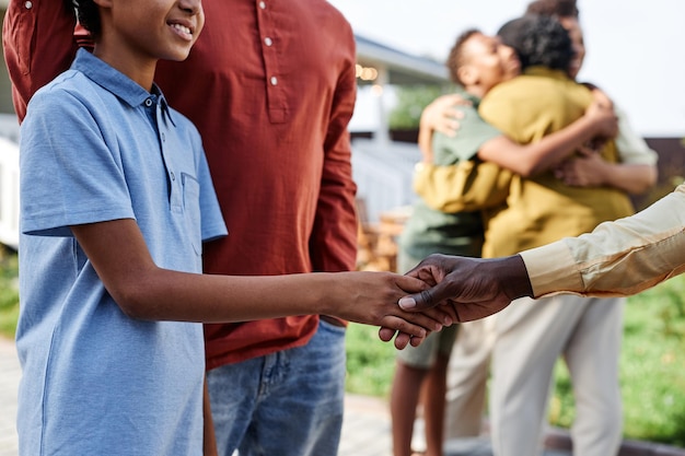 Side view closeup of young african american boy shaking hands with family member during summer party