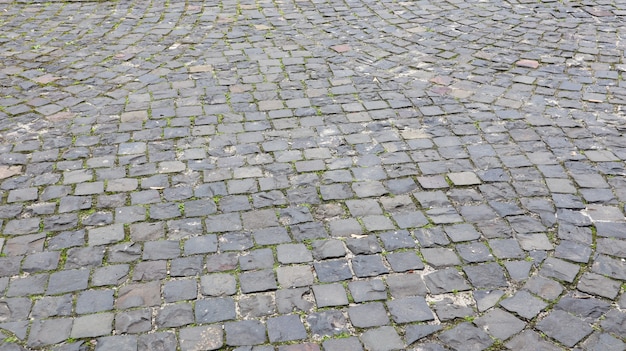 Side view of the cobblestones of the street. Detailed photo of the road surface. Traditional artwork on roads and sidewalks in the old part of the city.