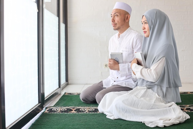 Side view of couple muslim holds holy book Quran at the mosque