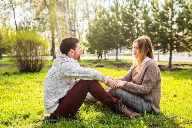 Photo side view of couple sitting on field against trees