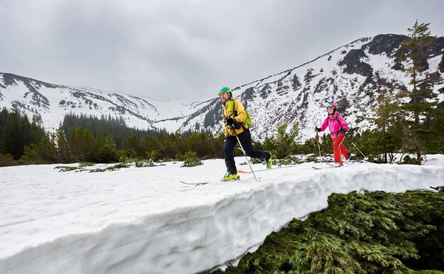 Side view of cross country skiers backpackers walking on ski in wooded mountains Snowcovered mountain in full altitude